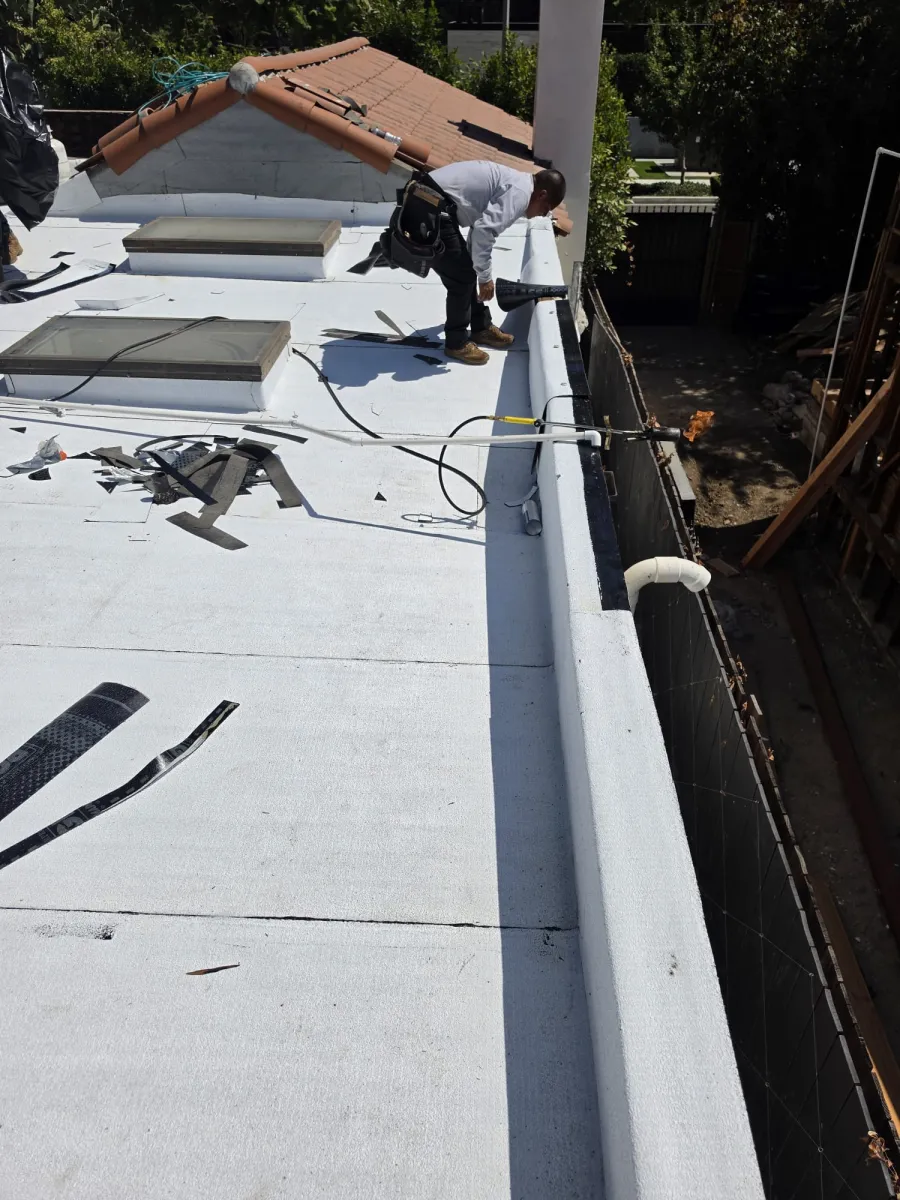Roofer working on membrane roofing beside skylights during an MDH project